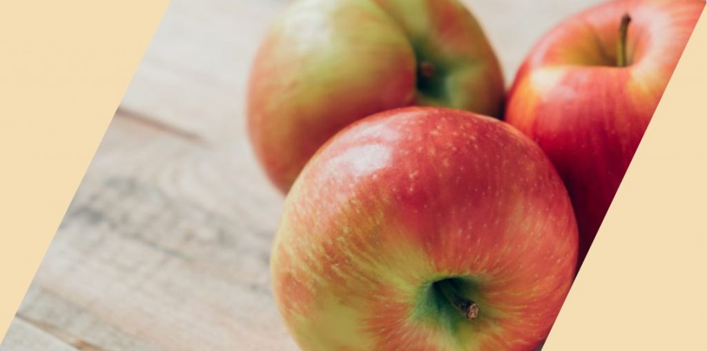 Three red apples with a wooden surface in the background