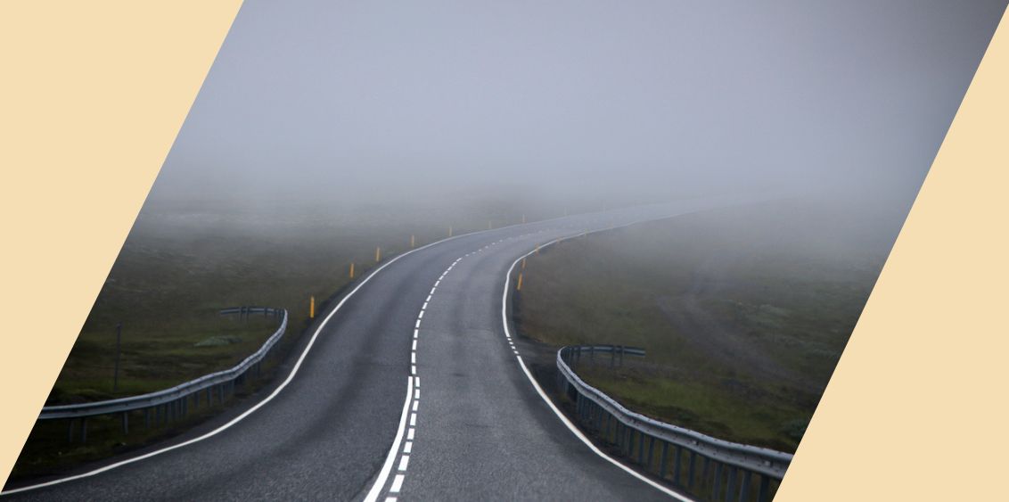 A winding road that disappears into a foggy background