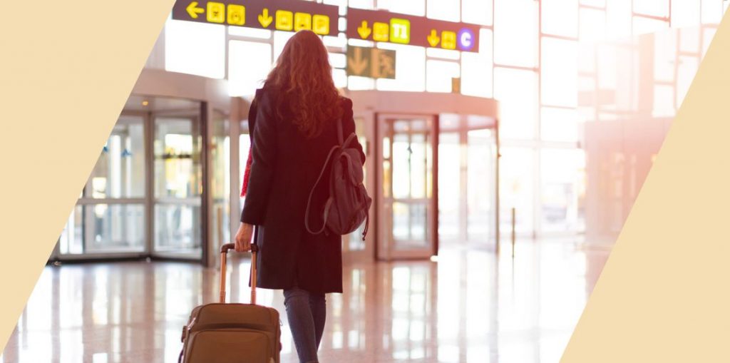 A person walking through the airport with a suitcase and backpack